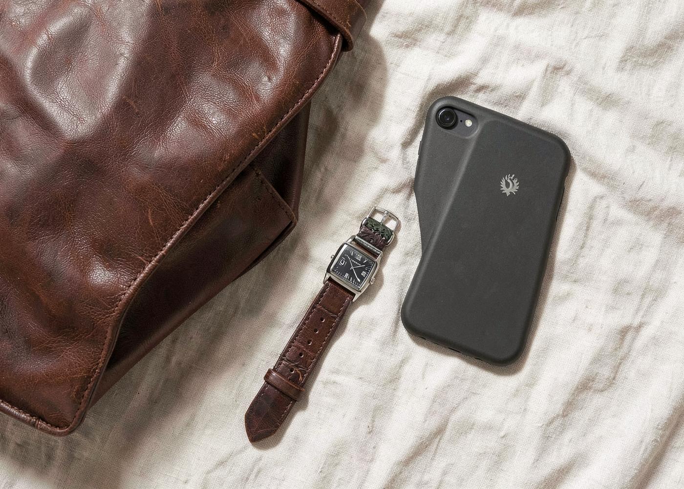 Leather bag, watch and phone case on linen